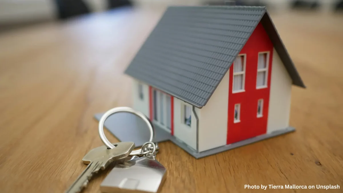 Model house and keys on a wooden table